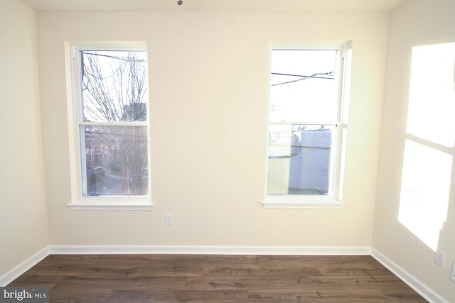 spare room with dark hardwood / wood-style floors and a healthy amount of sunlight