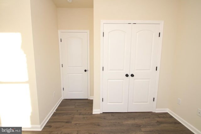 unfurnished bedroom with dark hardwood / wood-style floors and a closet