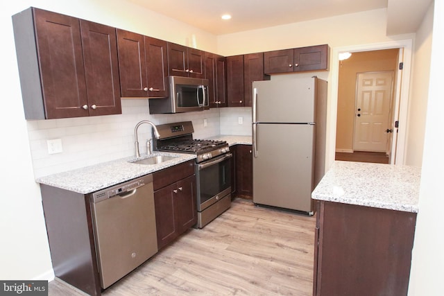 kitchen with stainless steel appliances, dark brown cabinets, sink, tasteful backsplash, and light hardwood / wood-style floors