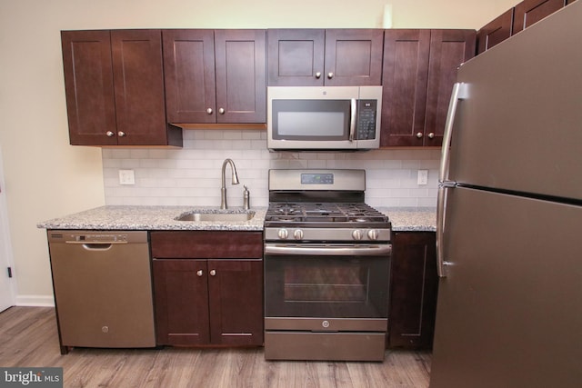 kitchen featuring light wood-type flooring, appliances with stainless steel finishes, sink, and decorative backsplash