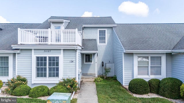 townhome / multi-family property featuring a balcony and a front lawn