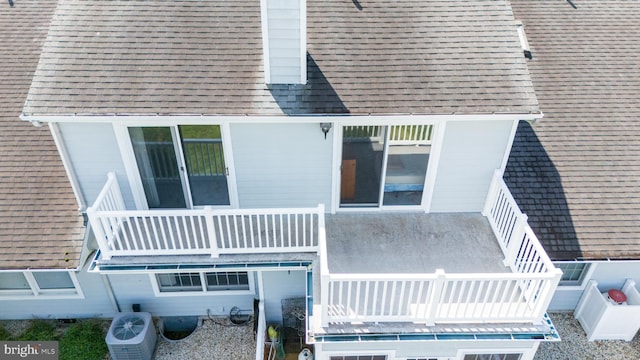 back of property with cooling unit and a balcony