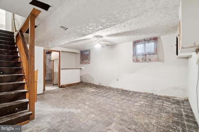 basement with ceiling fan and a textured ceiling