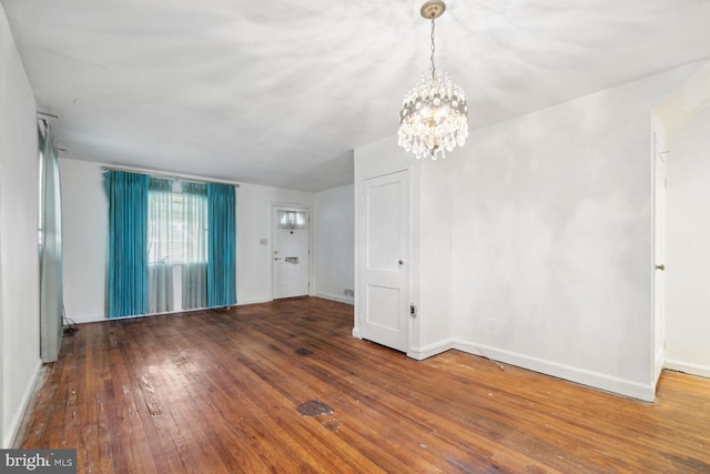 empty room with hardwood / wood-style floors and an inviting chandelier