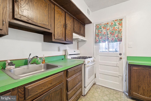 kitchen with sink, white range with gas stovetop, dark brown cabinetry, and light tile patterned floors