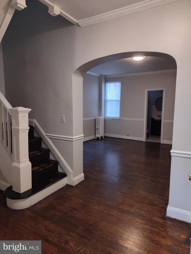 interior space featuring wood-type flooring, ornamental molding, and radiator heating unit