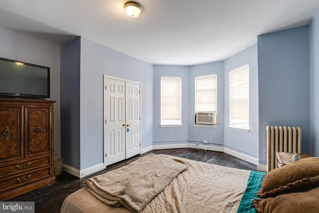 bedroom featuring a closet, radiator, dark wood-type flooring, and cooling unit