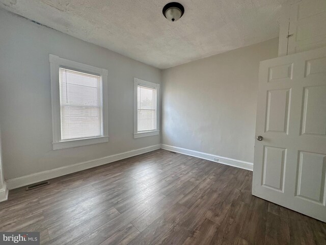 empty room with a textured ceiling and hardwood / wood-style flooring