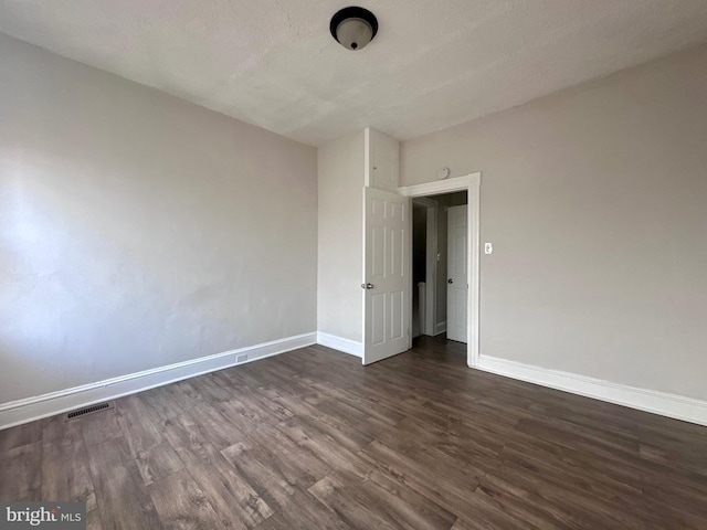 spare room with dark wood-type flooring and a textured ceiling