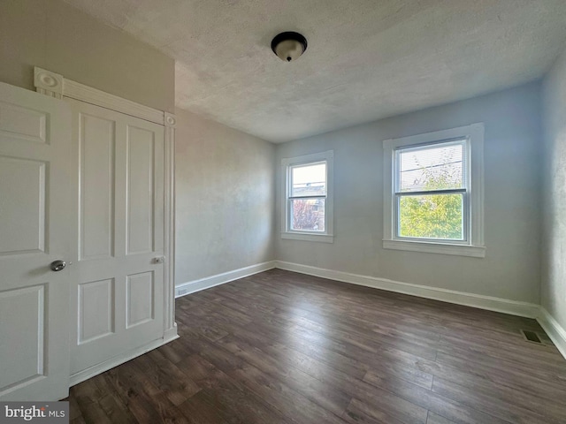 unfurnished room featuring dark wood-type flooring and a textured ceiling