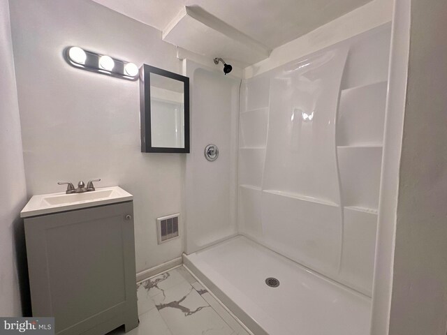 bathroom featuring vanity, a shower, and tile patterned flooring