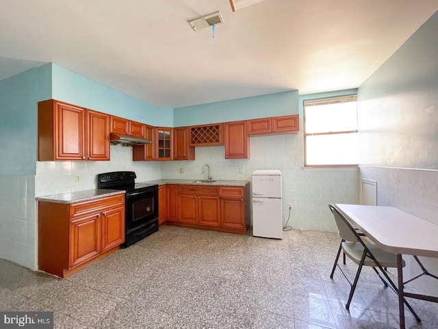 kitchen with light tile patterned flooring, white fridge, sink, and black range with electric stovetop