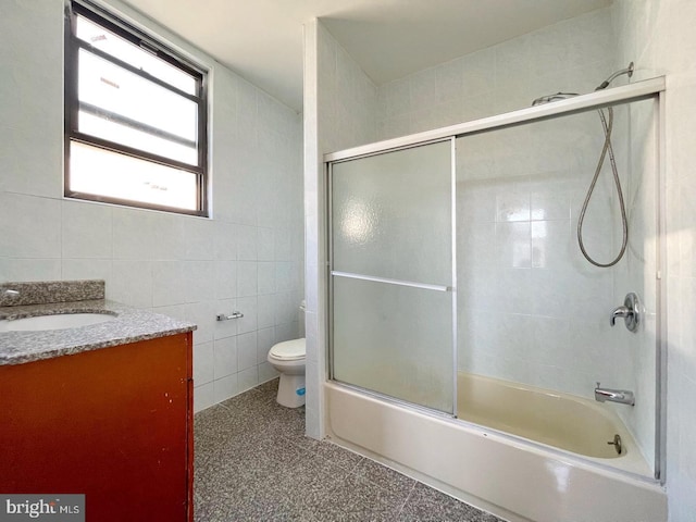 full bathroom featuring toilet, tile walls, shower / bath combination with glass door, tile patterned flooring, and vanity