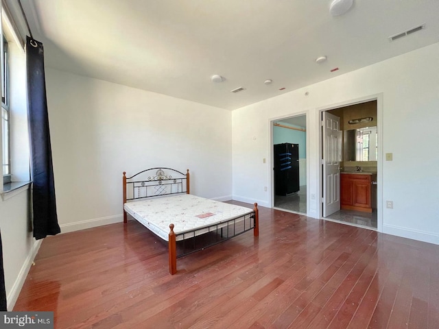 bedroom with ensuite bath and hardwood / wood-style floors