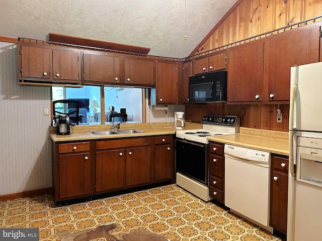 kitchen with wood walls, white appliances, sink, vaulted ceiling, and a textured ceiling