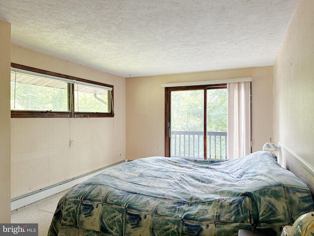 bedroom with access to outside, a textured ceiling, a baseboard radiator, and multiple windows