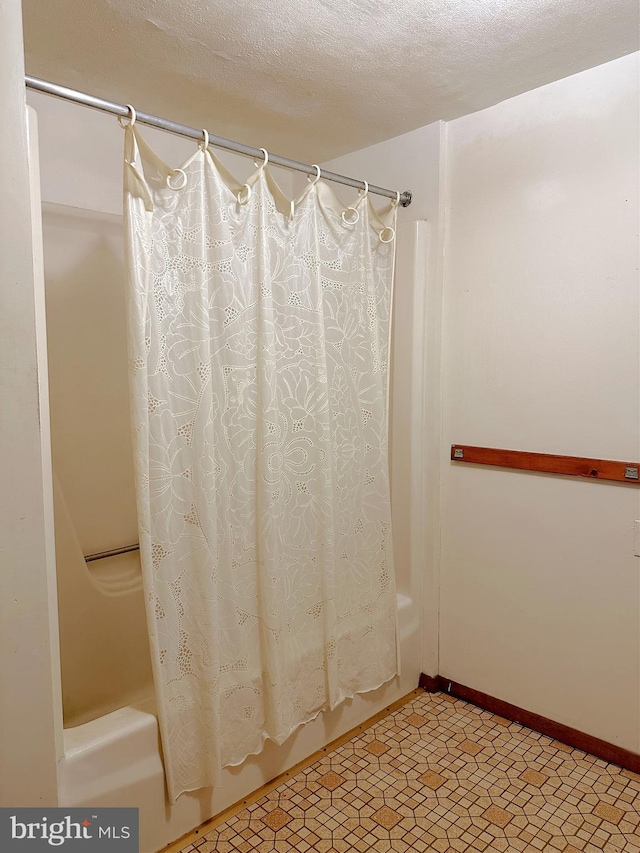 bathroom with shower / bathtub combination with curtain and a textured ceiling