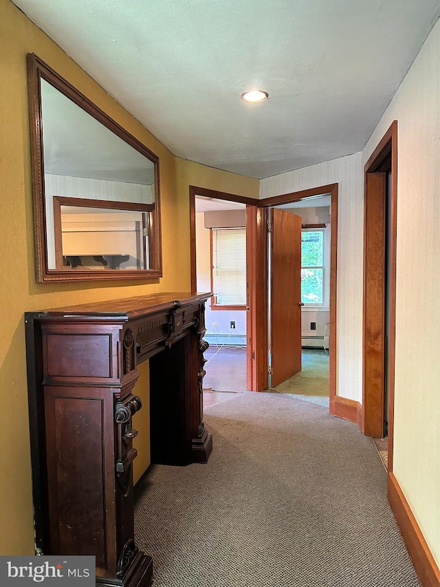 hall featuring carpet flooring, baseboard heating, and baseboards