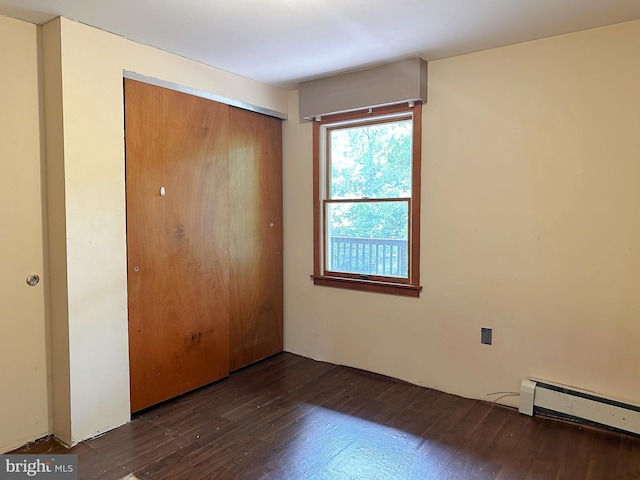 unfurnished bedroom featuring a baseboard heating unit, wood finished floors, and a closet