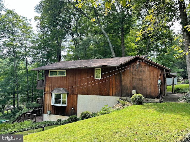 view of side of home with a yard and a balcony