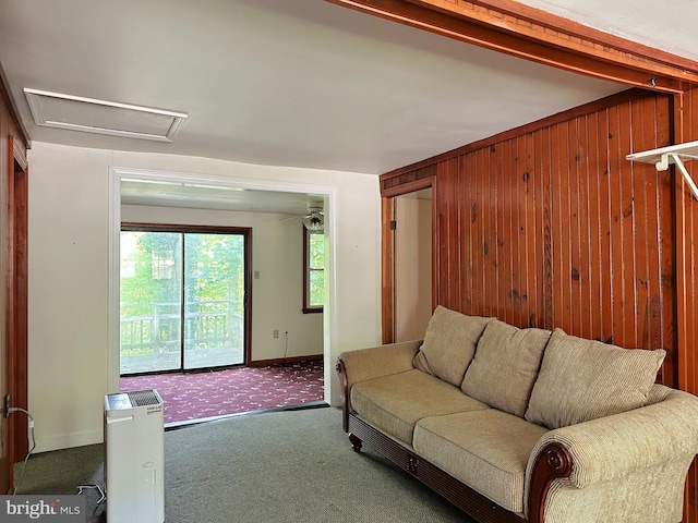 living room with beam ceiling, wood walls, and dark colored carpet