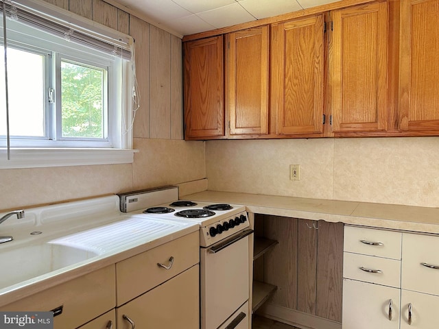 kitchen featuring white electric stove, light countertops, brown cabinets, and a sink