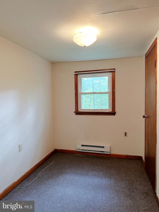 carpeted spare room featuring a baseboard heating unit