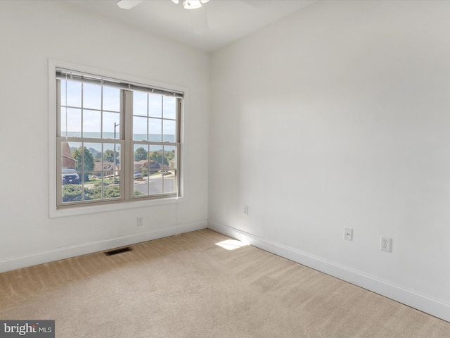 spare room with ceiling fan and light colored carpet