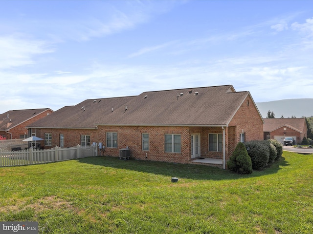 rear view of property with a yard and central AC unit