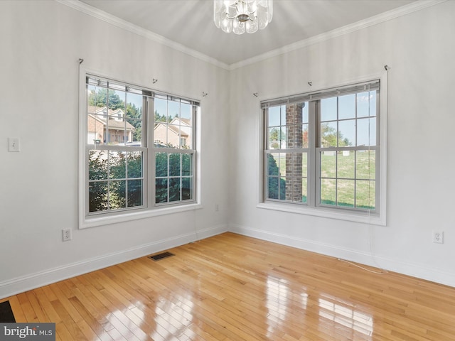 empty room with hardwood / wood-style floors, ornamental molding, and a notable chandelier