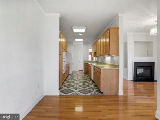 kitchen with crown molding, a multi sided fireplace, light wood-type flooring, and sink