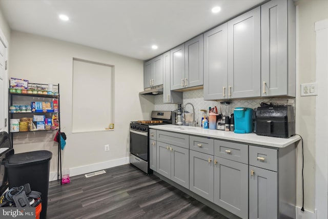 kitchen featuring decorative backsplash, dark wood-type flooring, gray cabinetry, gas stove, and sink