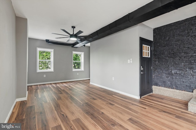 empty room featuring beamed ceiling, ceiling fan, and wood-type flooring