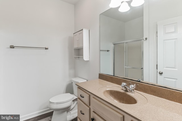 bathroom with hardwood / wood-style flooring, toilet, vanity, and a shower with shower door