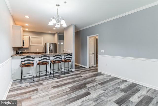 kitchen with stainless steel refrigerator, kitchen peninsula, white cabinetry, and wood-type flooring