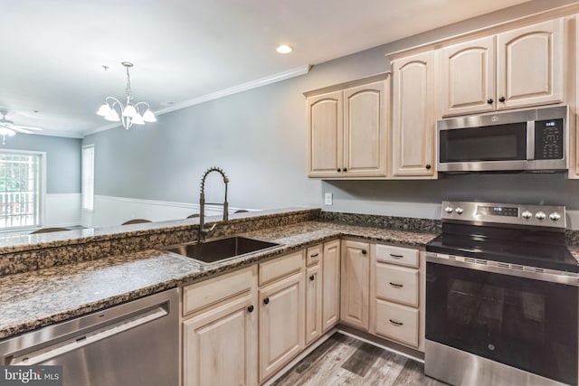 kitchen with stainless steel appliances, sink, light brown cabinets, ceiling fan with notable chandelier, and hardwood / wood-style flooring