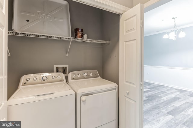 washroom featuring light hardwood / wood-style floors, a notable chandelier, crown molding, and washer and clothes dryer