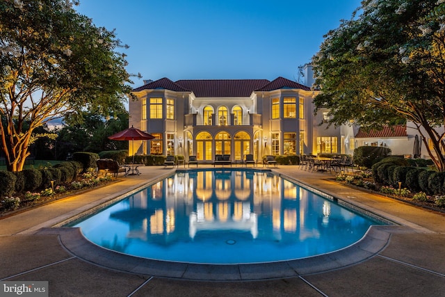 pool at dusk with a patio area