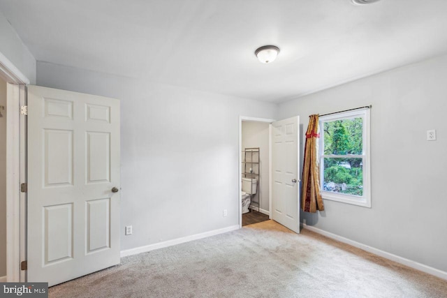 unfurnished bedroom featuring light carpet and baseboards