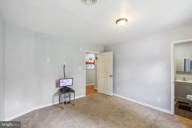 bedroom with connected bathroom, carpet floors, a sink, visible vents, and baseboards