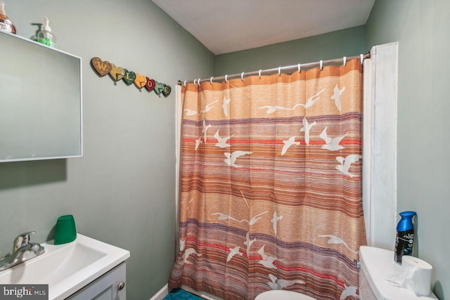 bathroom featuring toilet, curtained shower, and vanity