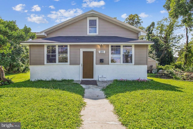 bungalow with concrete block siding and a front yard