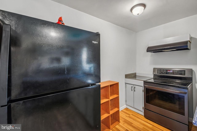 kitchen with open shelves, freestanding refrigerator, wall chimney exhaust hood, light wood finished floors, and stainless steel range with electric stovetop