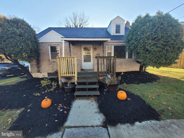 new england style home with brick siding and a front lawn