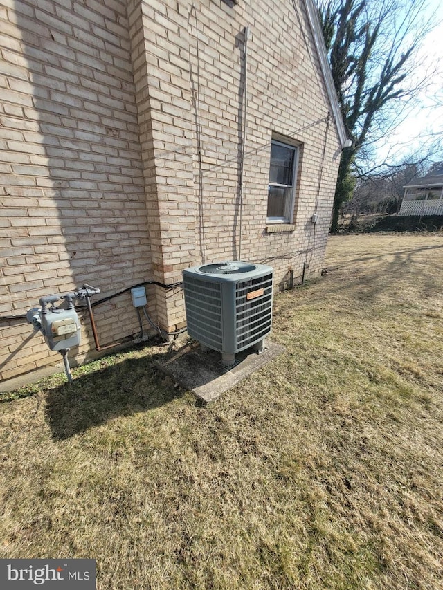 details with gas meter, central AC unit, and brick siding