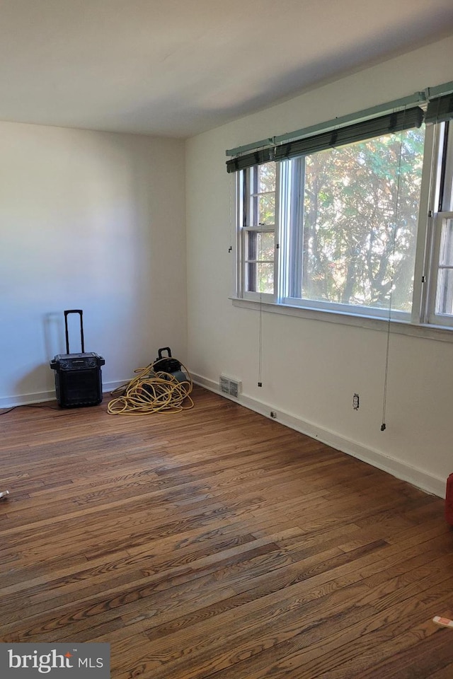 empty room with dark wood-style flooring and visible vents