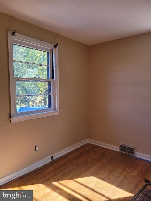 unfurnished room with baseboards, visible vents, and wood finished floors