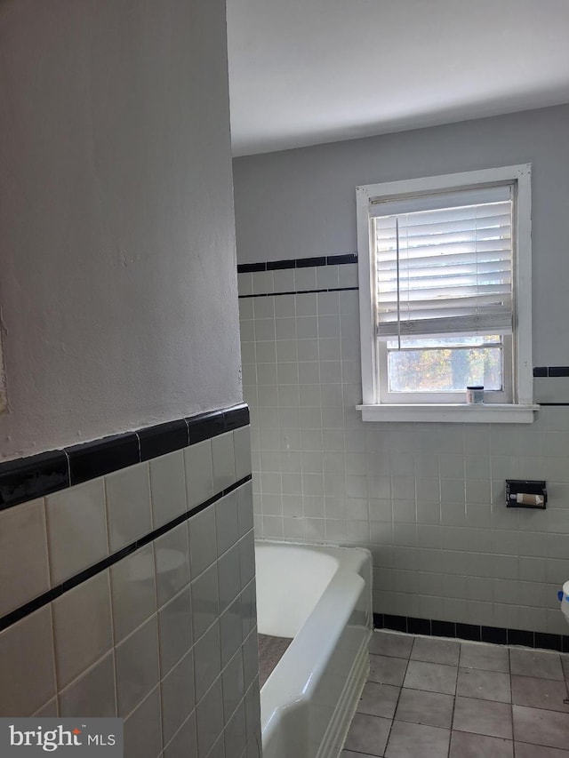 bathroom with tile patterned flooring, a bath, and tile walls