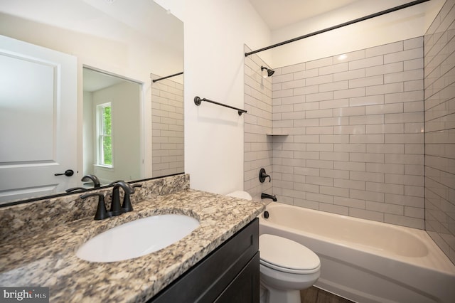 full bathroom with tiled shower / bath, vanity, and toilet