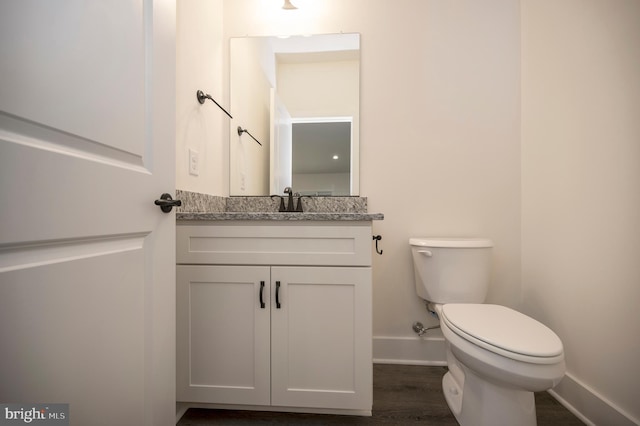 bathroom with wood-type flooring, vanity, and toilet